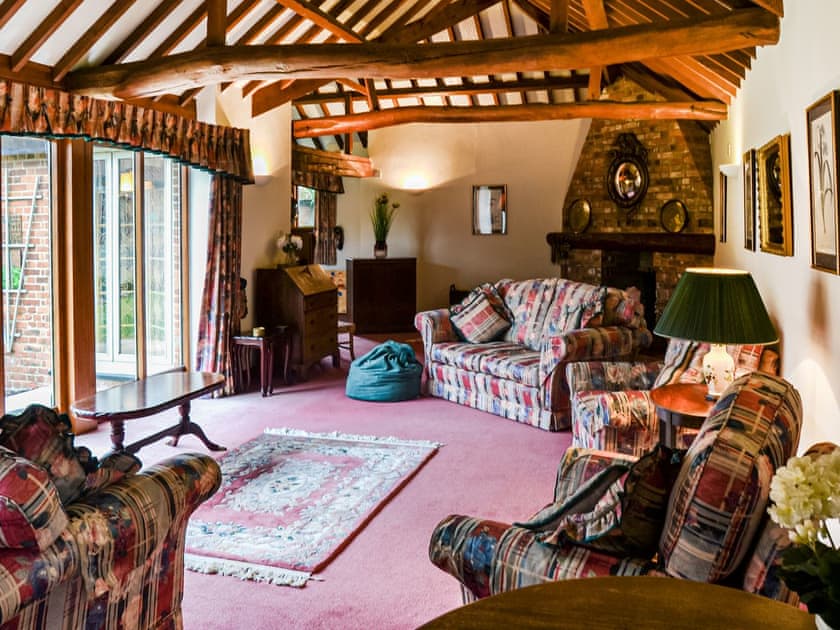 This is the largest room in the house, plenty of comfortable seating areas a library, TV and a woodburning stove | Lodge Farm Barn, South Walsham