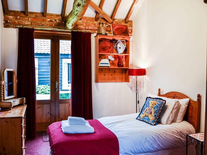 Miss Scarlett and Doctor Who must have met in a time warp. This single room is very calming and has French doors to the courtyard. | Lodge Farm Barn, South Walsham