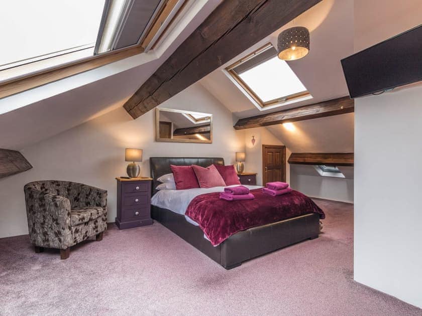 Beamed bedroom with leather bed | April Cottage, Windermere