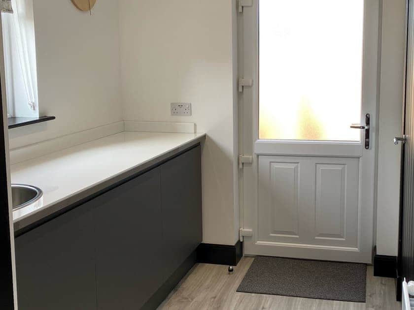 Utility room equipped with extra sink, washing machine and tumble dryer | Mile End Cottage, Inverness
