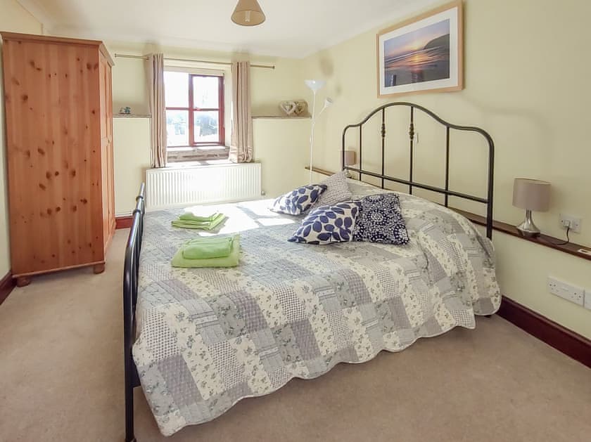 Front bedroom with its comfortable kingsize bed, wardrobe and a window on the babbling brook | Penybont Barn, Llangorse