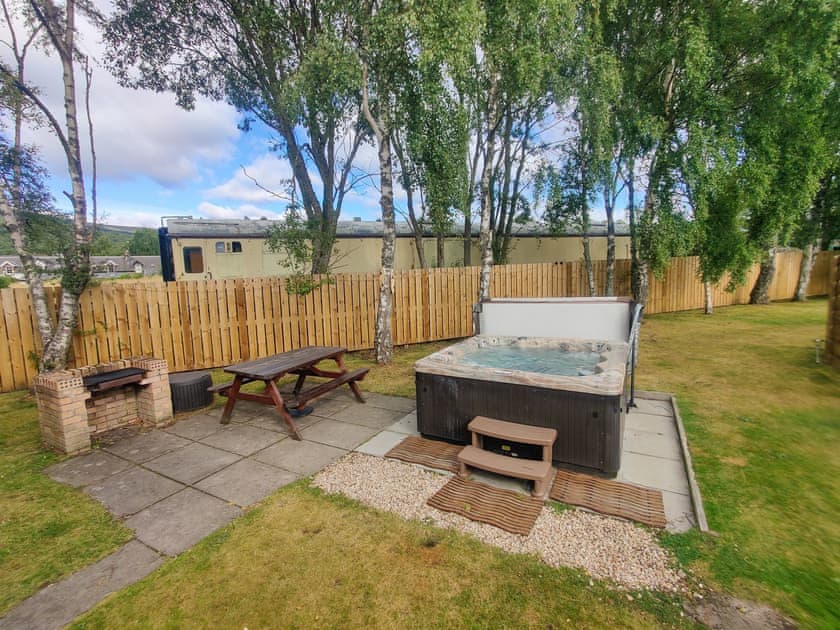Garden area with hot tub and some vintage Strathspey Steam Railway stock in the background  | Holly Lodge, Aviemore