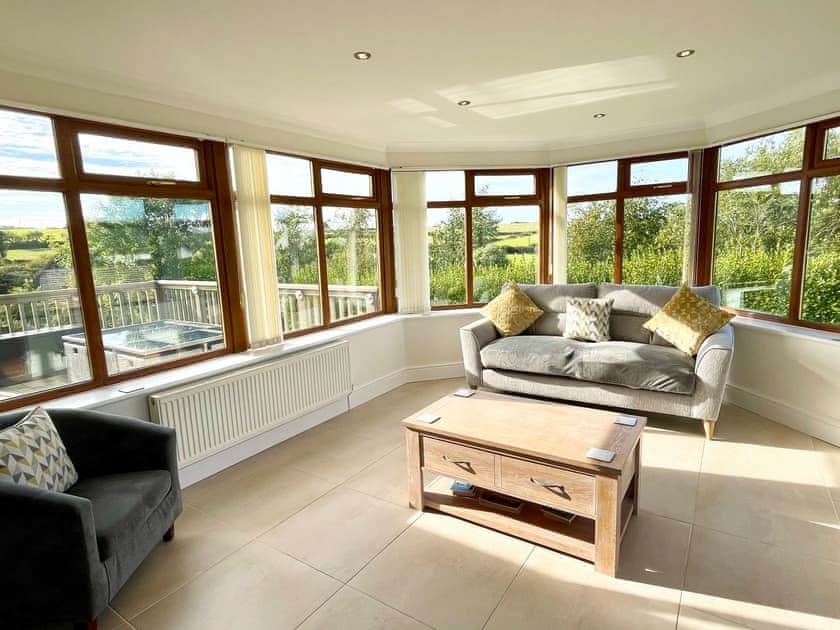 The bright and comfortable sunroom area overlooking open fields and onto the amazing coastline of northern Anglesey | Llwyn Ysgaw, Cemaes
