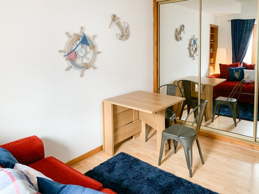 Sitting room dining table and an extra TV behind the centre sliding door | Seahaven Cottage, Portknockie