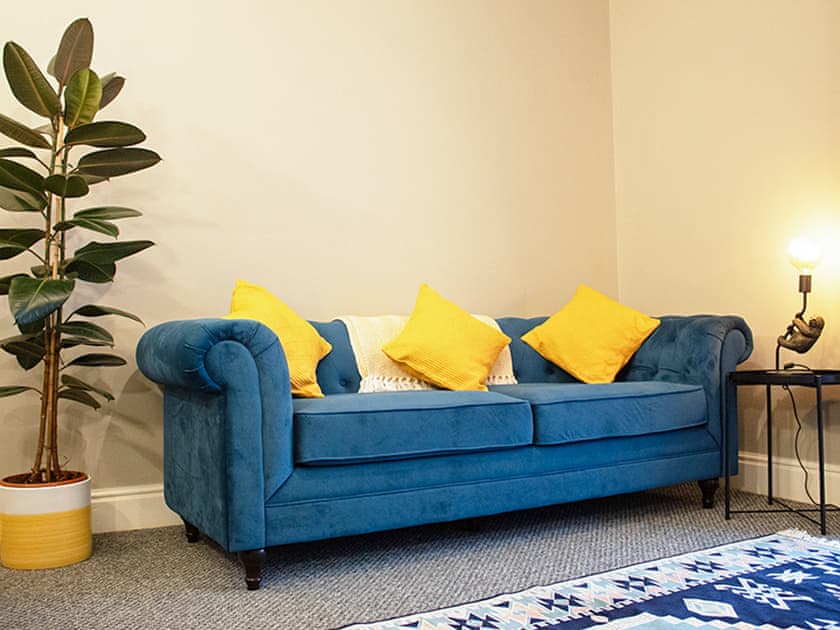 Second living space with cosy soft velvet chesterfield sofas with blankets and cushions to help you relax. | Captain’s Cottage, Shanklin