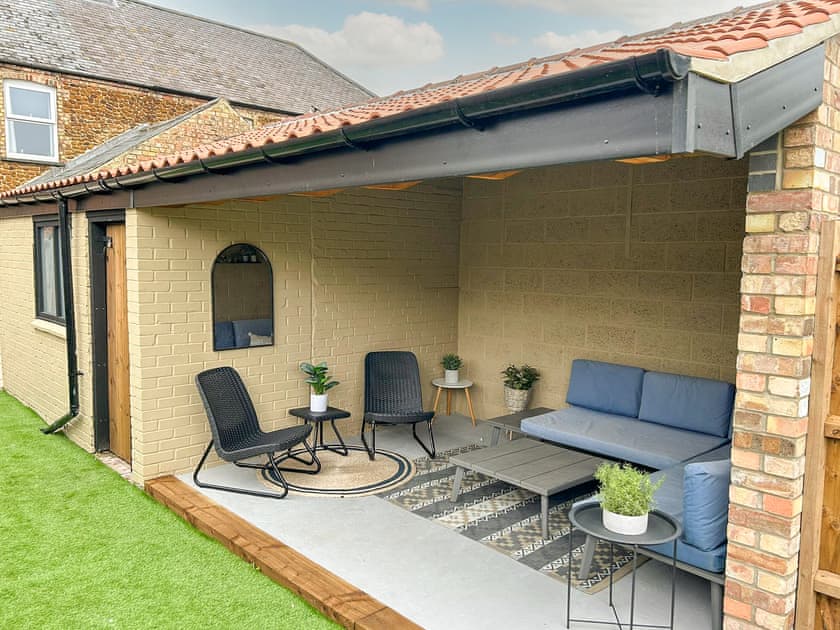 Under cover seating in the garden | Florence Cottage, Heacham