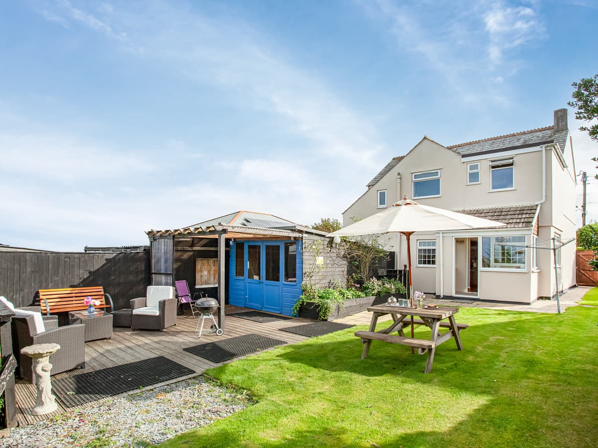 Tanglewood rear garden with lawn, picnic table, deck seating and blue summerhouse in Stenalees