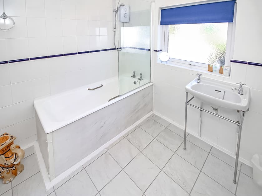 Bathroom with an electric shower over the bath and sink  | Sea View House, Borth Y Guest, near Porthmadog
