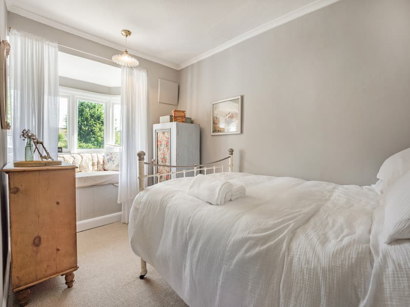 Double bedroom with large cushion filled bay window seat that looks over the garden. It is the perfect ’Book Nook’, but also has a comfortable mattress for a 3rd child to sleep. Bedding on request. | Greenfield Cottage 1866, Worthing