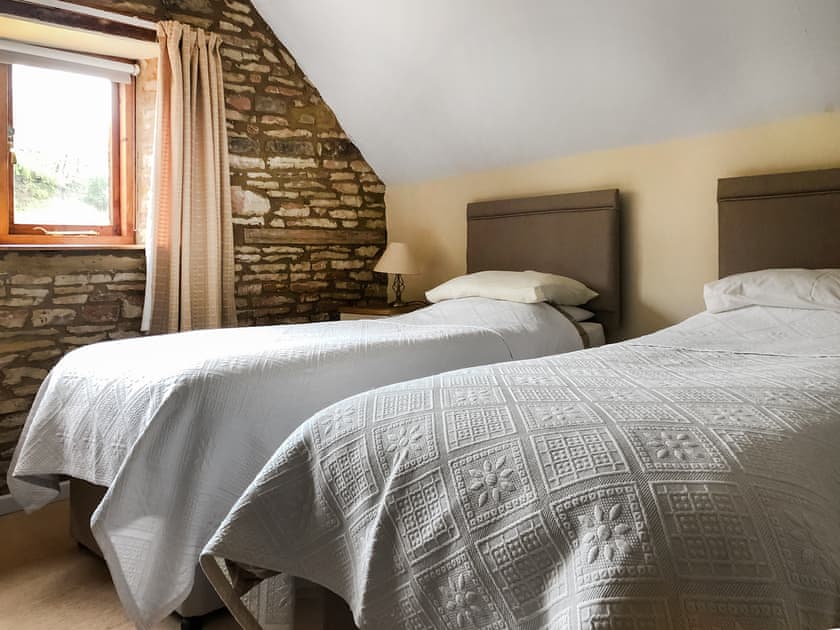 Twin bedroom with exposed stone feature wall | The Mill House, Lea, near Ross-on-Wye