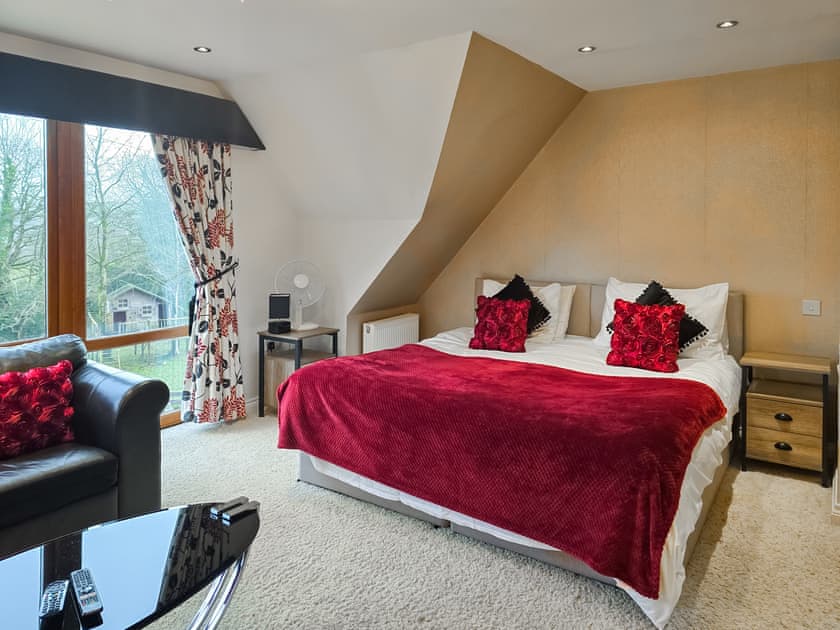 Bedroom 2 is very spacious with superking bed, single bed, sofa and coffee table overlooking the front garden | Wernddu Fechan House - Wernddu Properties, Neath