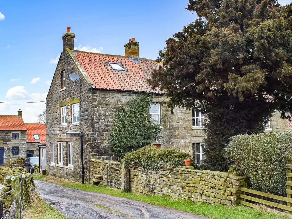 Stone exterior of Gable End Cottage with a red tiled roof beside a country lane in Goathland