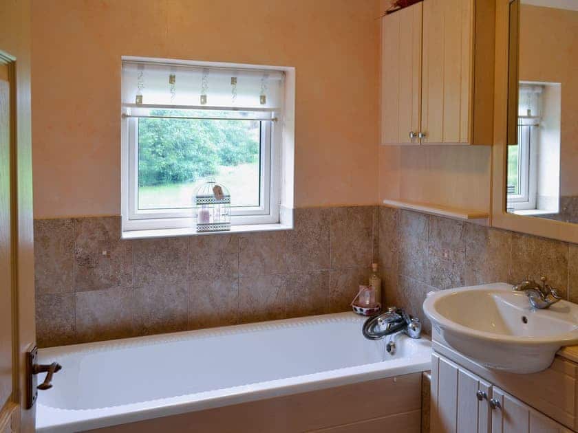 The half-tiled bathroom has a shower over the bath | Carreg Y Garth Isaf, Rhiwlas near Bangor