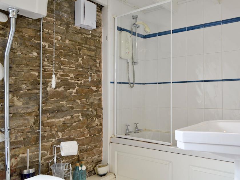 Beautiful bathroom with stone feature wall and a shower above the bath | Cattlemarket Cottage, Hawes