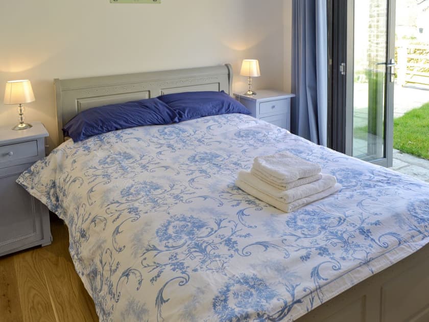 Comfortable double bedroom with bi-fold doors and en-suite shower room | Kataluma, Praa Sands, near Penzance