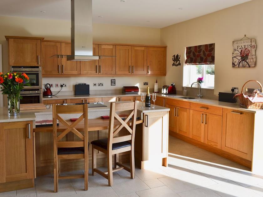 Dining room/kitchen with breakfast bar, TV, tiled floor and bi-fold doors to patio | Birchfield, Rhuallt, near St Asaph