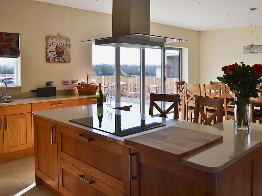 Dining room/kitchen with breakfast bar, TV, tiled floor and bi-fold doors to patio | Birchfield, Rhuallt, near St Asaph