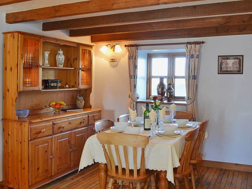 The farmhouse style table and dresser complement the dining area’s wooden floor and exposed beams | Coachmans Cottage, White Cross, near Newquay