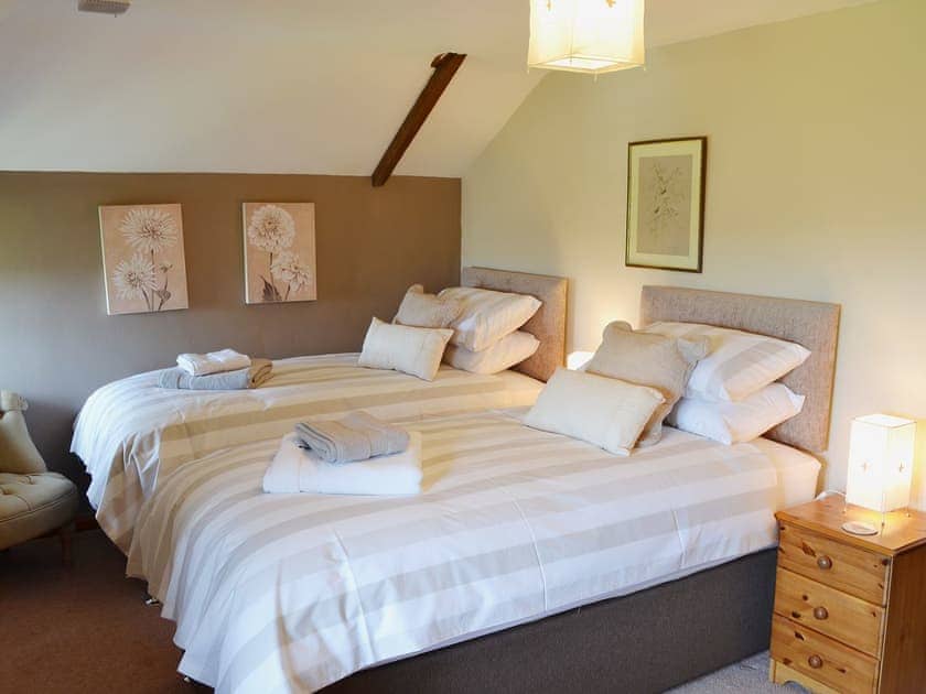 The cosy and romantic double bedroom has sloping ceilings | Coachmans Cottage, White Cross, near Newquay