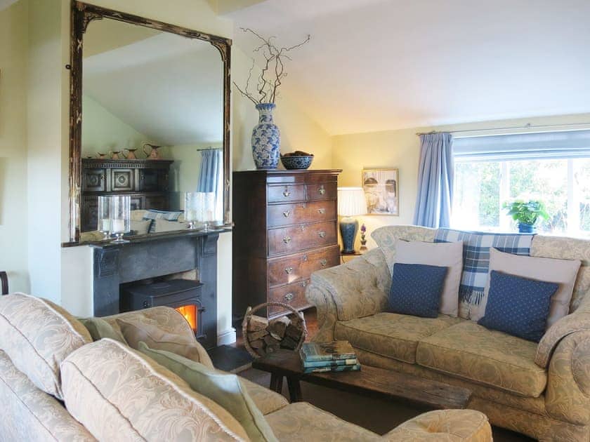 The living room has exposed beams, a wooden floor and woodburning stove | The Coach House - Berrington House, Tenbury Wells