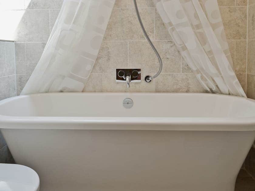 The bathroom has a shower over the roll top bath | The Coach House - Berrington House, Tenbury Wells