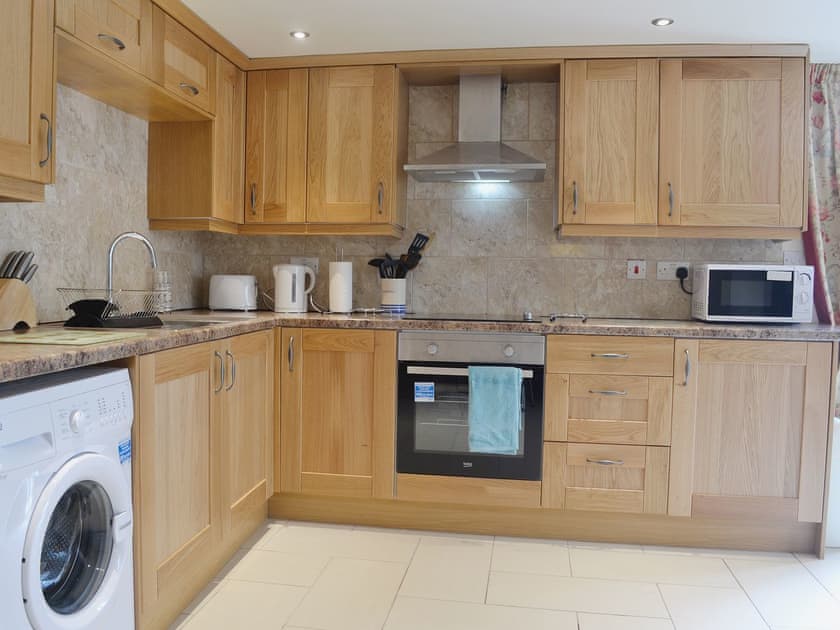 Granite worktops and complementary tiling in the kitchen area gives a clean and chic appearance | Yr Wyddfa - The Old School, Caeathro, Caernarfon
