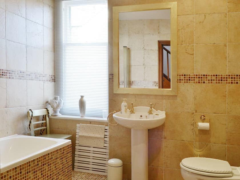 The fully tiled bathroom has a heated towel rail and a shower over the bath | Oak Lea, Keswick