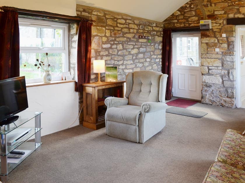 The living room has exposed stonework walls and original features | Garden Cottage, Edlingham, near Alnwick