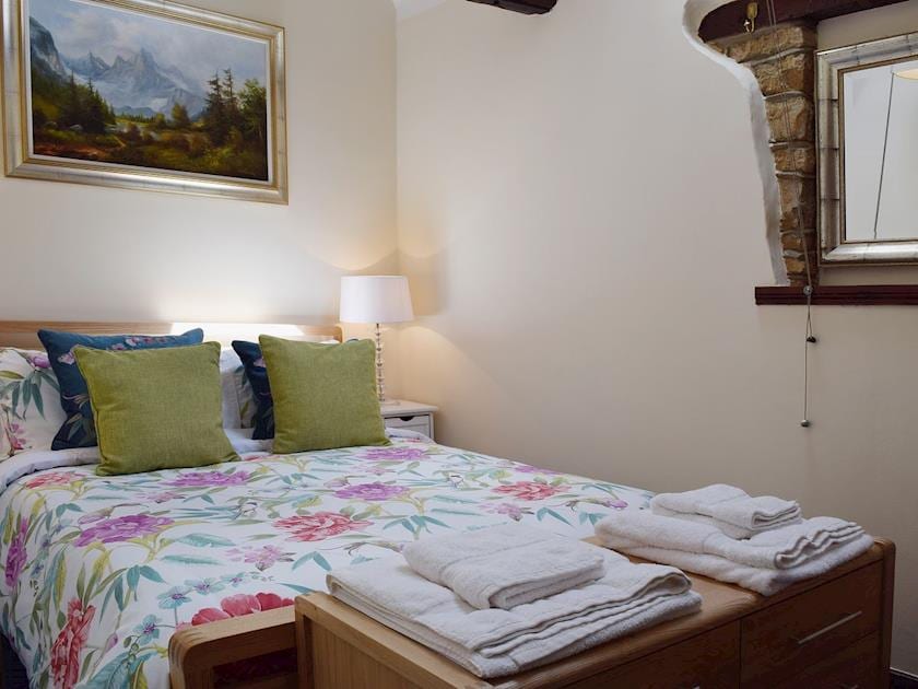 The bedroom has beams and exposed original brickwork | Yew Tree Cottage - River Nene Cottages, Water Newton, near Peterborough