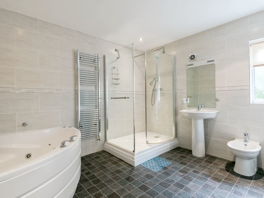 Bathroom with jacuzzi bath, shower cubicle and toilet | Oaklands, Langrigg, near Cockermouth