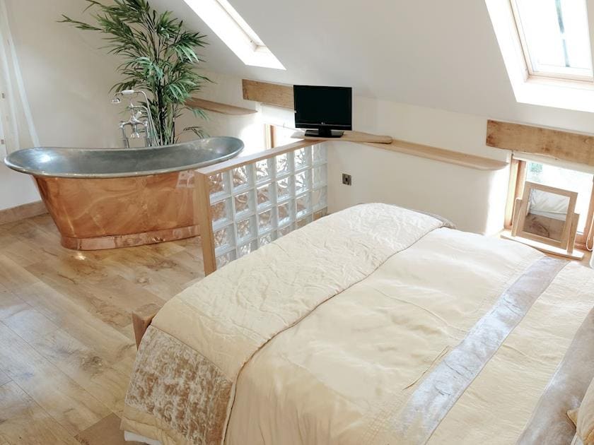 Luxurious bedroom featuring a copper bateau bath | Corn Keep - Wooldown Holiday Cottages, Marhamchurch, near Bude