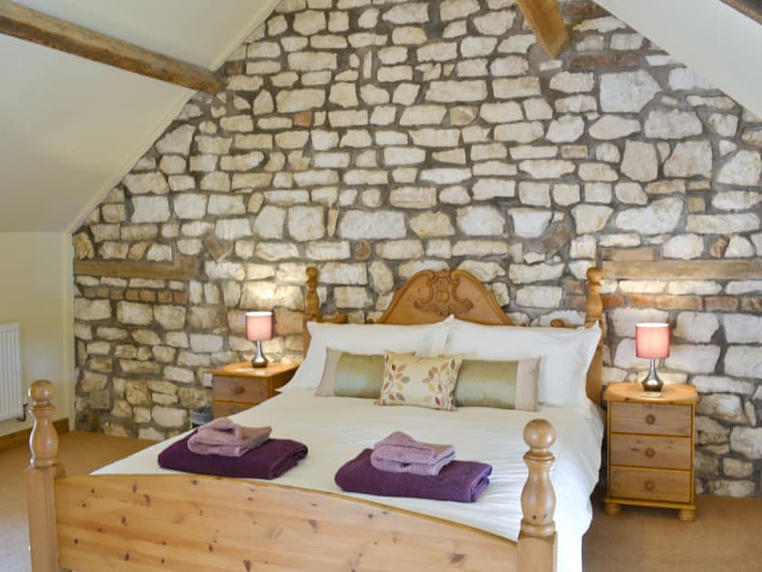 Exposed stone feature wall in double bedroom | Puffin Cottage - Manor Farm Cottages, Buckton, near Flamborough