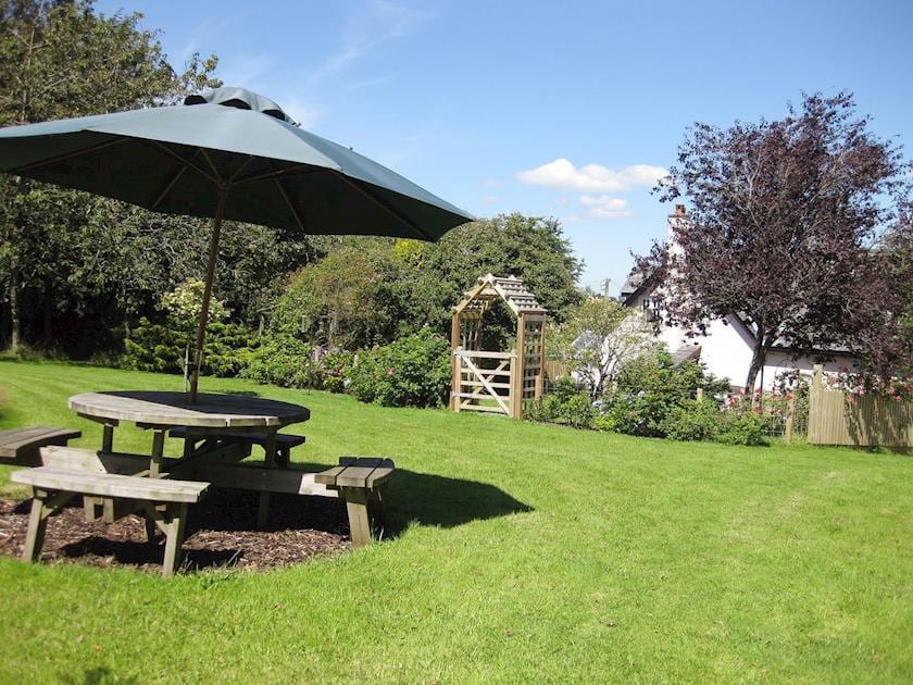 A thoughtfully placed outdoor eating area taking advantage of the large lawned garden | Peartree Cottage, Northlew, near Okehampton