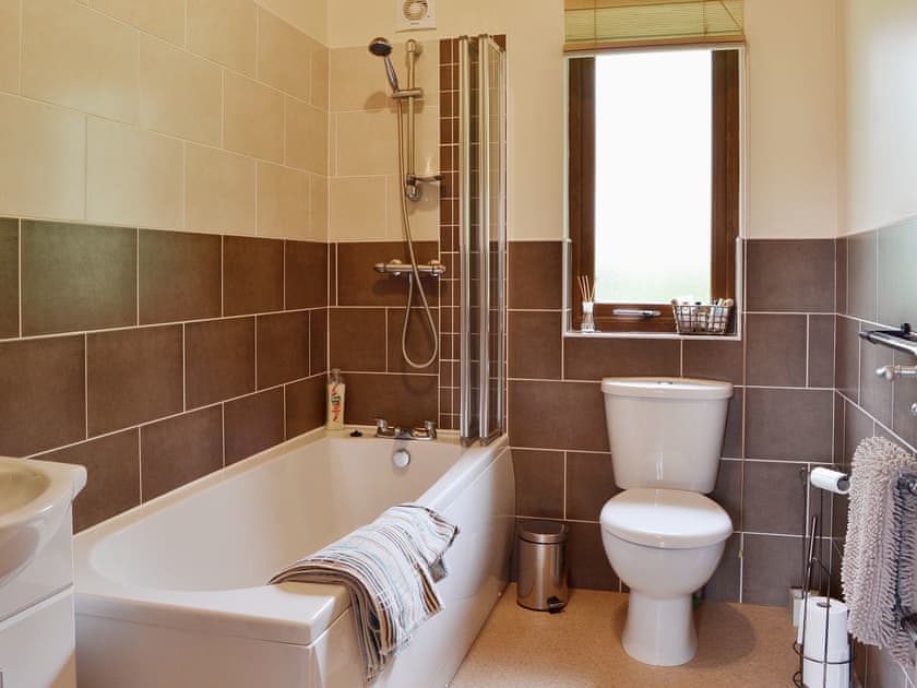 The bathroom features a shower over the bath | Rowanburn Lodge, Greystoke, near Penrith
