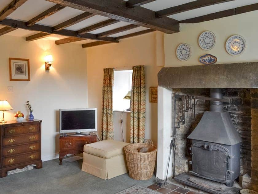 Feature fireplace with wood-burner and exposed wood beamed ceiling in living room | , 