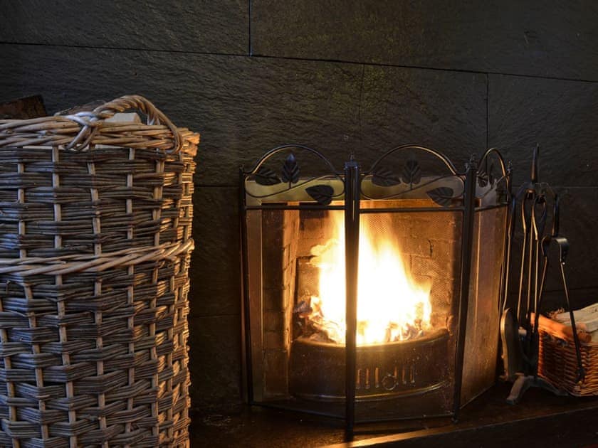 A roaring fire in the open fireplace in the living room | Woodsedge, Palnackie, Castle Douglas