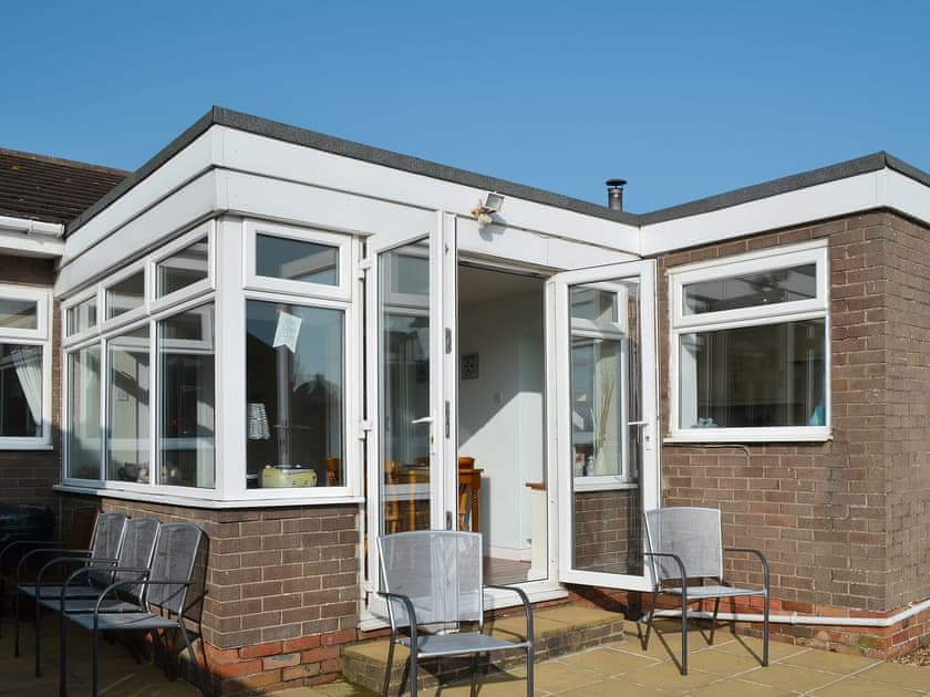 Sun room with patio doors and ample seating | Longstone Bungalow, Beadnell