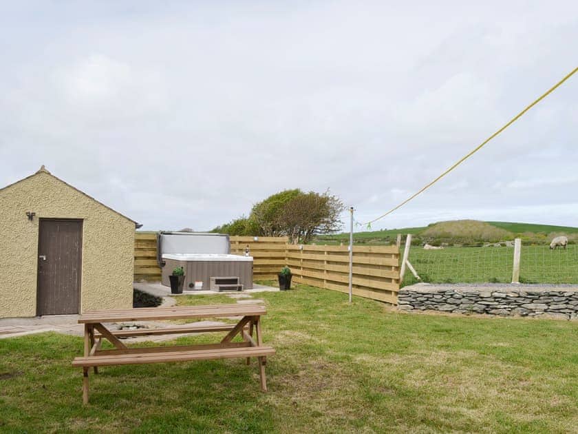 Garden area with outdoor furniture and hot tub | Llofft Storws - Bronallt Barns, Llanynghenedl, near Holyhead