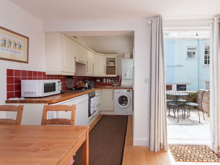 Modest dining area and kitchen with access to balcony | Kitcat Cottage, Dartmouth
