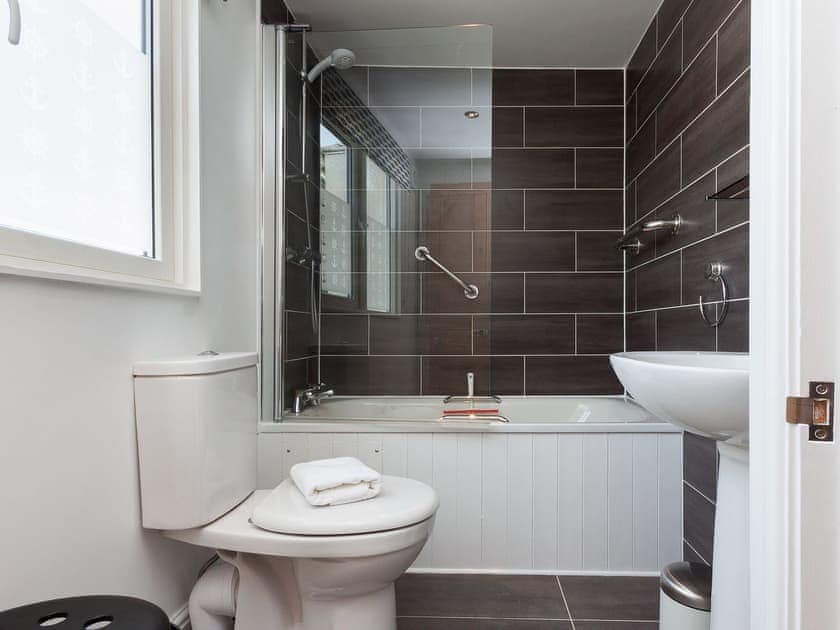 Beautifully tiled bathroom with shower over the bath | Kitcat Cottage, Dartmouth