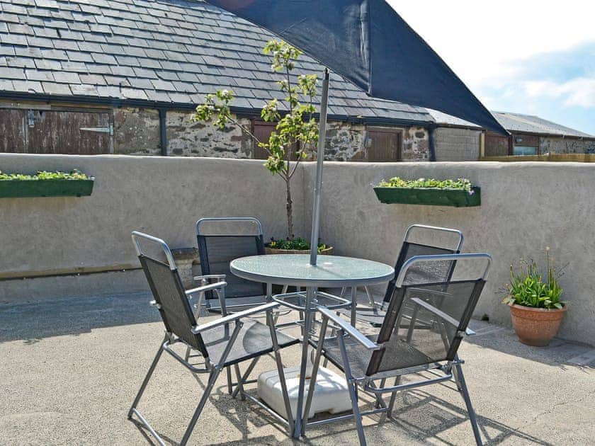 Courtyard with outdoor dining furniture | Ty Main Cottage, Newborough, near Llangefni