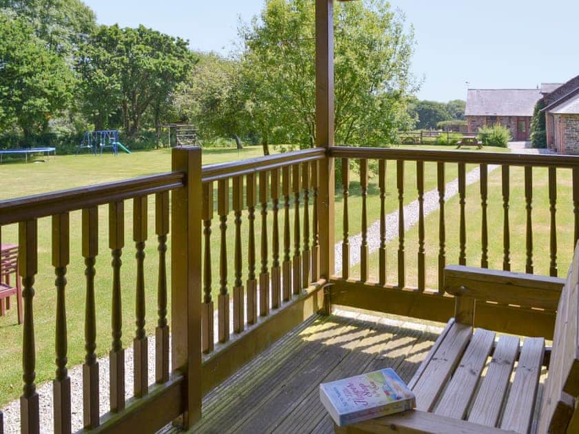 Covered and enclosed decked veranda area | Tarka’s Holt Log Cabin - Stowford Lodge Holiday Cottages, Langtree, near Great Torrington