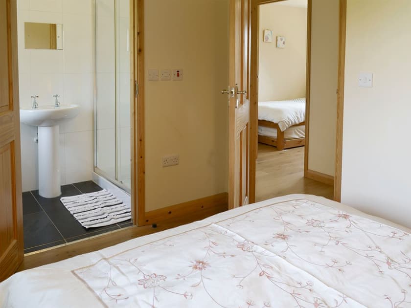 Comfortable double bedroom with en-suite shower room | Tarka’s Holt Log Cabin - Stowford Lodge Holiday Cottages, Langtree, near Great Torrington