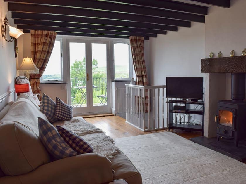 Living room with wood burner and patio doors leading to balcony | Y Teras, Rosebush, near Narberth