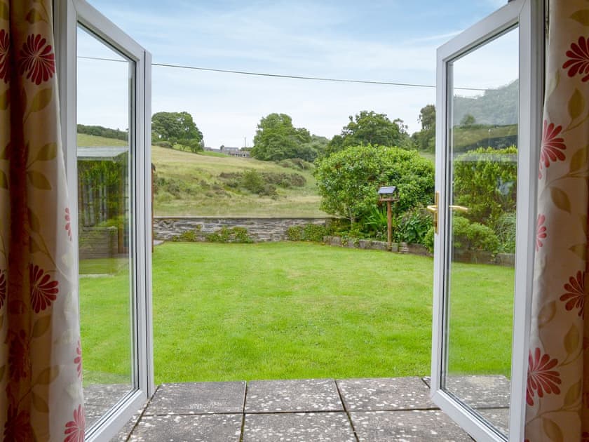 Patio doors lead directly to the private garden and summerhouse with table and chairs | Nant y Bwthyn, Dol-y-Bont, near Borth
