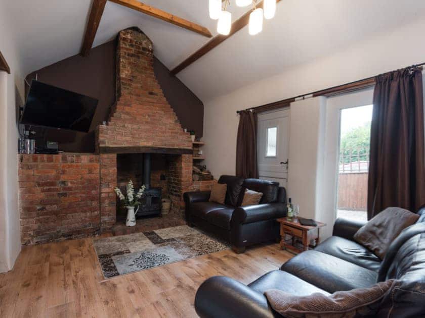 Living room with exposed brick fireplace & wood burning stove | Bakers Barn, Bransgore, near Christchurch