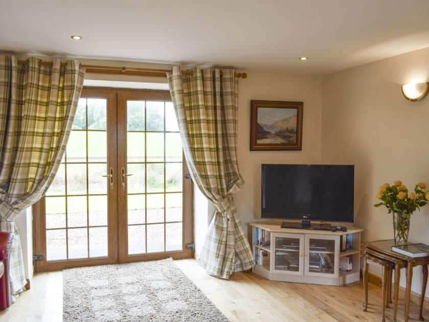 Living room with double doors to rear patio and garden | The Ploughmans - Loch Lomond Farm Cottages, Balfron Station, near Stirling