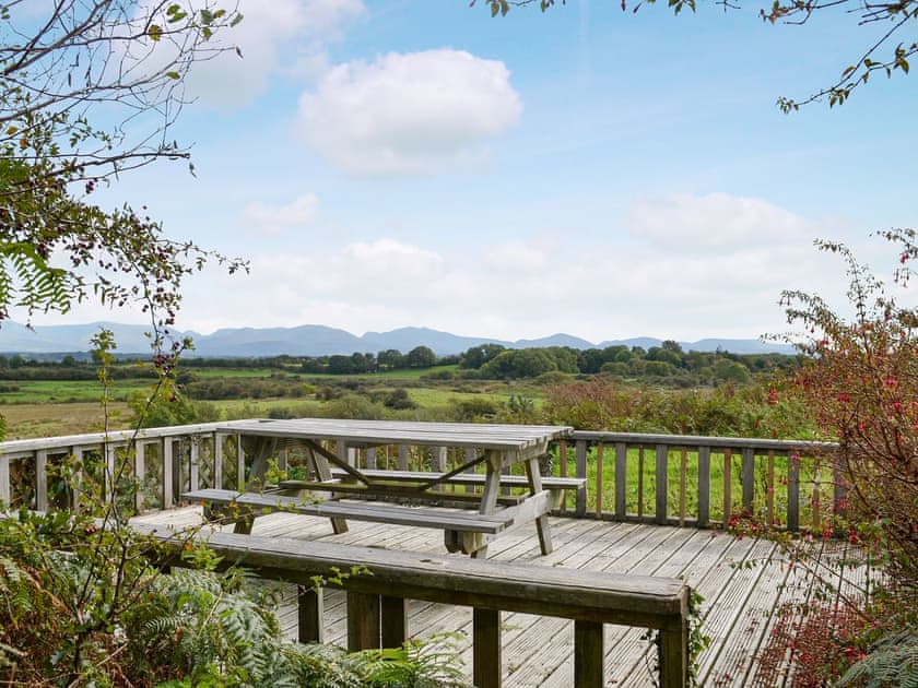 Lovely decked area, a perfect spot to admire the far-reaching views across to the mountains of Snowdonia | Pant Y Mel, Llanbedrgoch, near Benllech