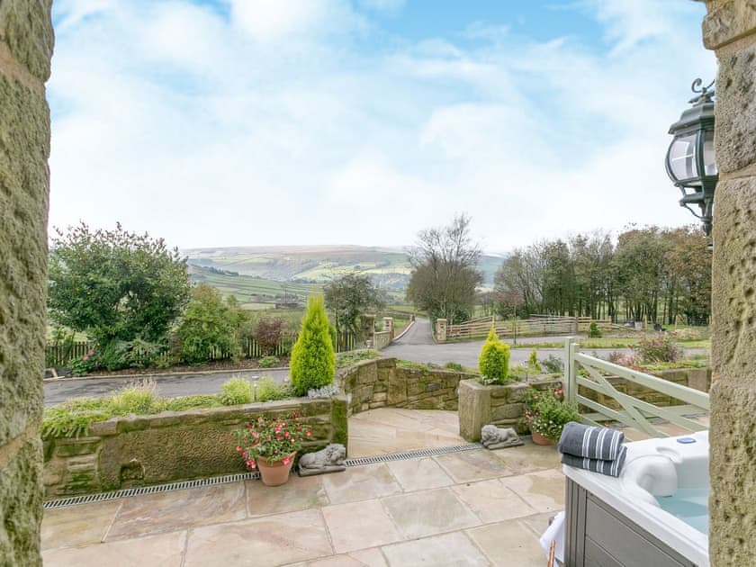 Luxurious hot tub sits on one side of the south-facing, flagstone patio with fantastic views | Commons Farm Cottage, Wadsworth, near Hebden Bridge