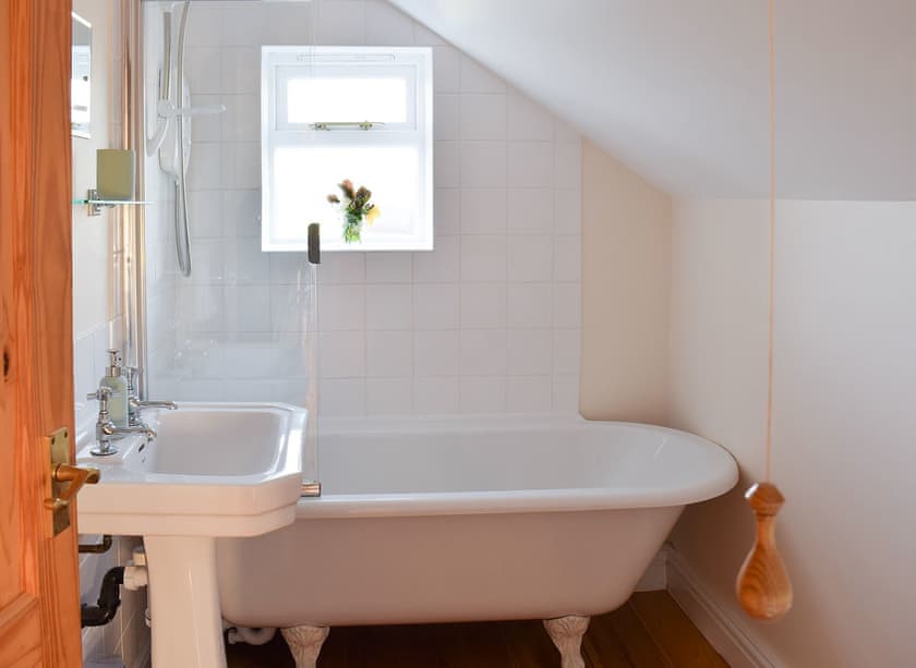 Lovely bathroom with standalone bath with shower overhead | Rowan Cottage, Aislaby, near Whitby